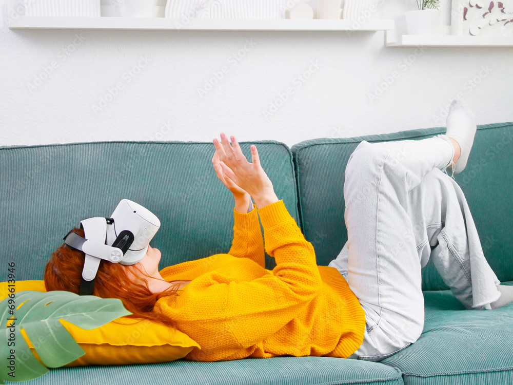 woman laying on sofa relaxing and playing VR and using futuristic artificial intelligence at home.. the concept of metaverse, virtual reality, future, technology, and internet of things.