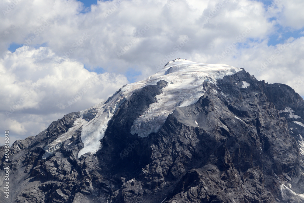 A glacier in the Italian Alps on the top of the mountains in a few clouds.