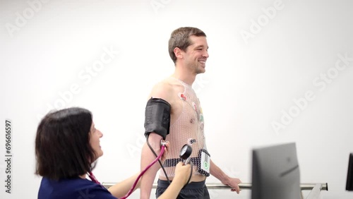 Video of a friendly female cardiologist checking blood pressure of a patient during cardiac stress test