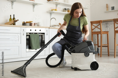 Young woman vacuuming carpe...