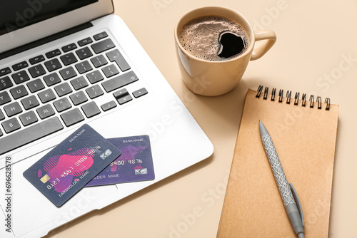 Laptop with credit cards  notebook and coffee cup on beige background  closeup. Online shopping