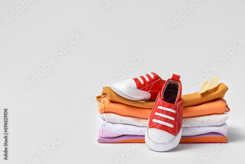 Stack of baby clothes and booties on white background