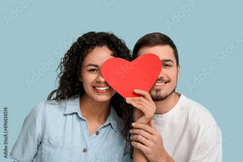 Young couple with paper heart for Valentine's day on blue background