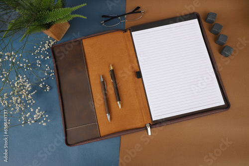 Leather Zipper Portfolio. Concept shot, top view, flap portfolio in brown colors and leather pen. Custom background flap portfolio view. Zipper portfolio on desktop. photo