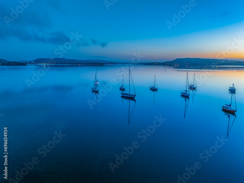 Aerial sunrise waterscape with boats, reflections and low cloud photo