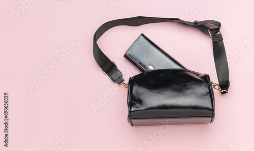 A woman's purse sticking out of a woman's leather bag on a pink background.