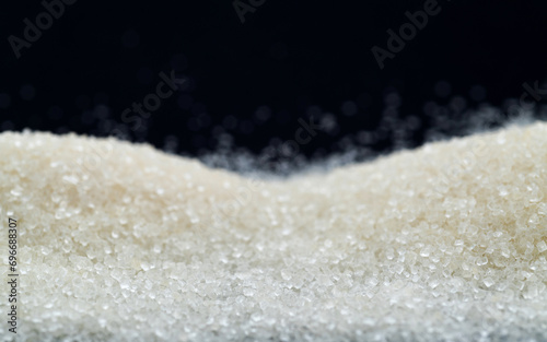 Pile of white sugar crystals on black background