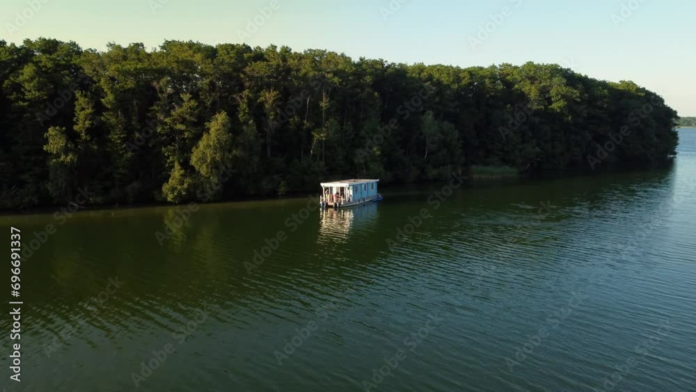 Houseboat floating on a green natural lake next to an island in Brandenburg, Germany Houseboat floating on a green natural lake next to an island in Brandenburg, Germany