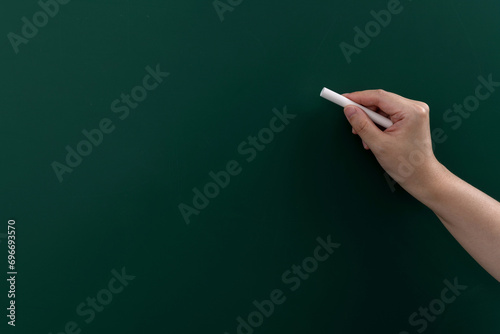 Hand holding chalk writing on chalkboard