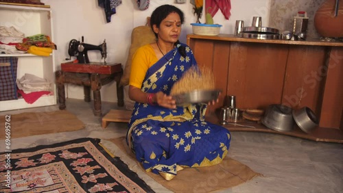 A middle-aged lady in her late forties - cleaning wheat  household daily chores  Indian home  lower middle-class single lady. A rural housewife from a village is picking dirt particles from the ric... photo