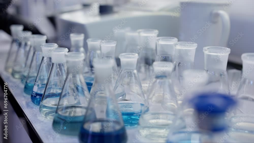 Scientific laboratory. A row of flasks stand on the table. Handheld camera, close-up, slow motion. A worker moves containers for chemicals. Scientific laboratory. A row of flasks stand on the table. Handheld camera, close-up, slow motion. A worker moves containers for chemicals.