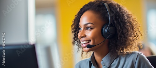 Female African-American call center employee wearing headphones, working in an office, providing customer service and consulting assistance. Female CRM specialist offering computer-based customer