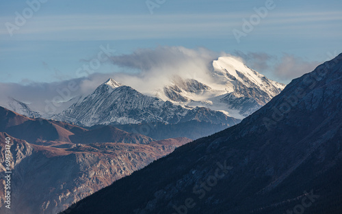 A snow and glacier covered mountain peak disappears in a cloud, Yukon Territory, Canada