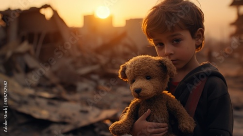 A young boy is seen holding a bear in front of a building that has been destroyed. This image can be used to depict themes of resilience, innocence, and the aftermath of a disaster
