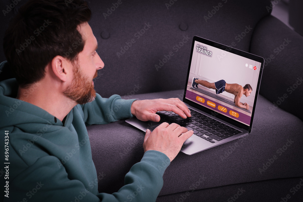 Personal trainer online. Man viewing website via laptop at home Personal trainer online. Man viewing website via laptop at home