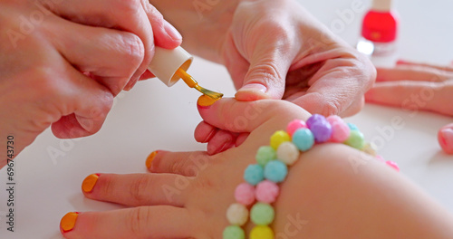 Mother paints her little daughters on the table, beauty ritual