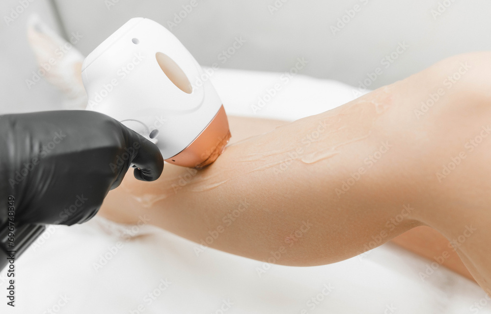 Naklejka premium a young woman lies with her eyes closed and raises her hand up during the laser hair removal procedure. laser hair removal of the whole body.