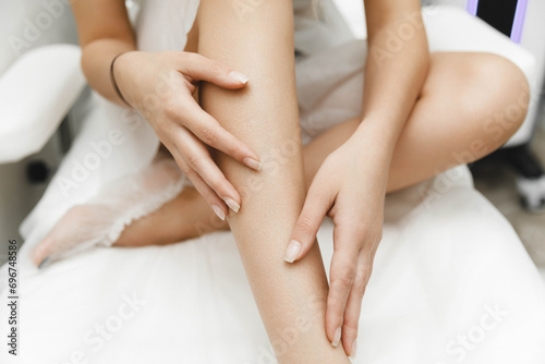 a young woman lies with her eyes closed and raises her hand up during the laser hair removal procedure. laser hair removal of the whole body. photo