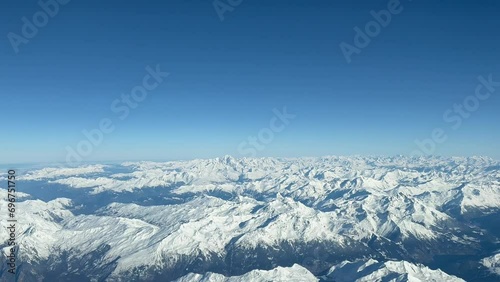 Aerial view of The Alps Mountains shot from a jet cockpit during a real flight in a splendid and bright winter morning with the peaks snowed. A pilot’s perspective at 10000m high. photo