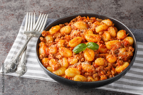 Italian potato gnocchi cooked with meat Bolognese sauce close-up in a plate on the table. Horizontal