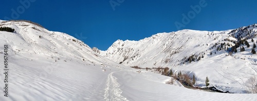 ski touring tracks in fresh snow going in beautiful alpine valley under blue sky