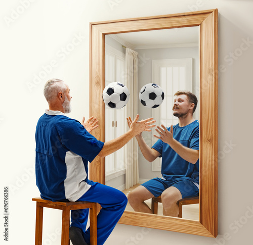 Senior man in uniform sitting with football ball near mirror with reflection of his younger self. Conceptual collage. Concept of present, past and future, age, life cycle, generation, ad