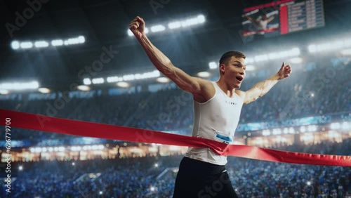 Fit Athlete Finishing a Sprint Run at a Crowded Arena with Cheering Spectators. Young Man Crossing the Finish Line with a Red Ribbon. Cinematic Super Slow Motion Sports Footage photo