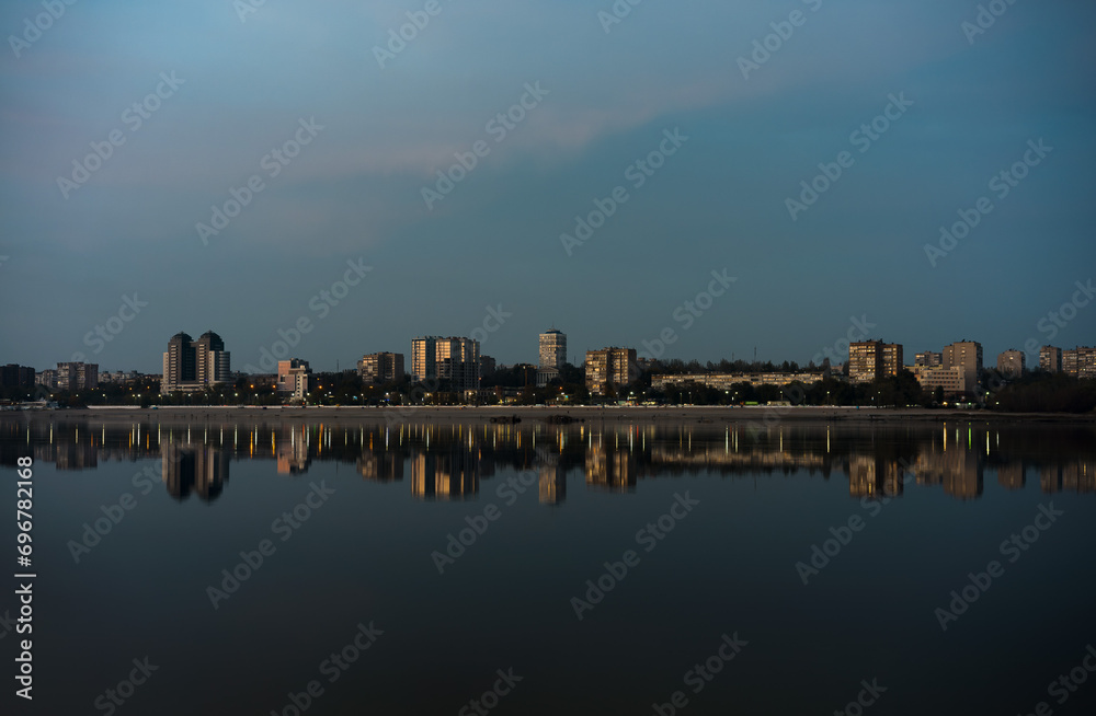 Evening cityscape on the banks of a wide river with tall buildings Evening cityscape on the banks of a wide river with tall buildings
