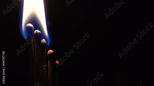 Five matches light up and burn on a black background, close photo