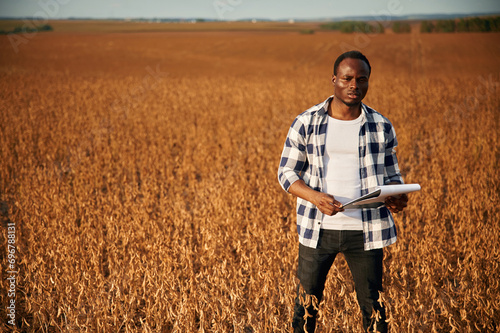 Holding documents in hands. Beautiful African American man is in the agricultural field