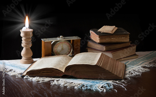 Old bible on the background of a clock and a candle
