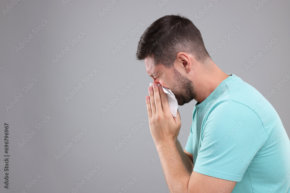 Allergy symptom. Man sneezing on light grey background. Space for text Allergy symptom. Man sneezing on light grey background. Space for text