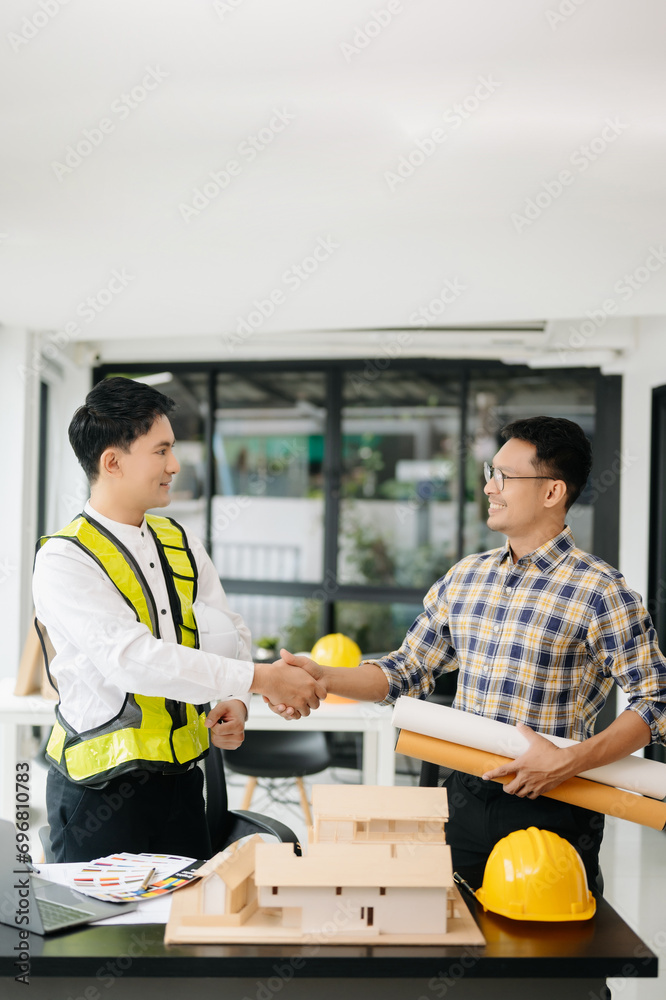 Construction team shake hands greeting start new project plan behind yellow helmet on desk in office Construction team shake hands greeting start new project plan behind yellow helmet on desk in office