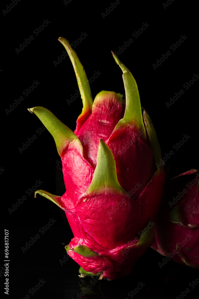 View of pitaya or pink dragon fruit on black background, vertical, with copy space