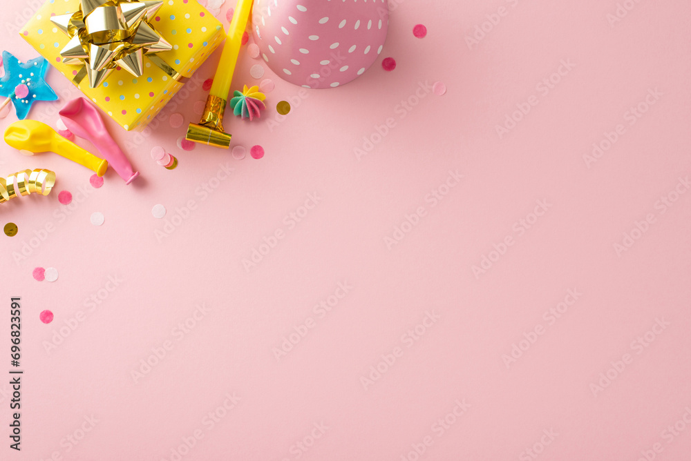 Sweet birthday display idea. Top view festive table featuring charming decor, candies, wrapped gift, celebratory hat, pipe, balloons, confetti, serpentine on pale pink background. Text-friendly space