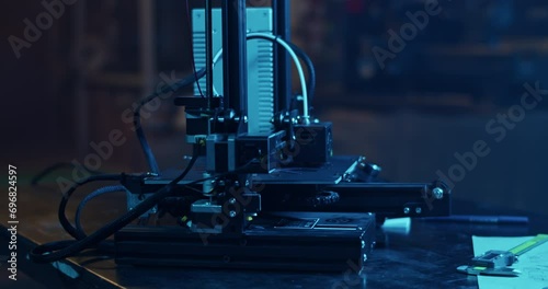 3D printer with filament spool making plastic detail in dark garage photo