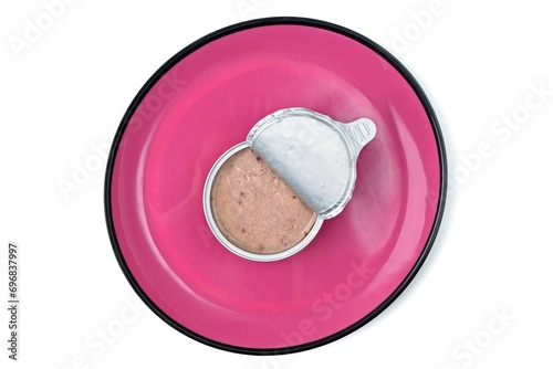 Open package of wet pet food on pink plate, seen directly from above. Isolated on white background.