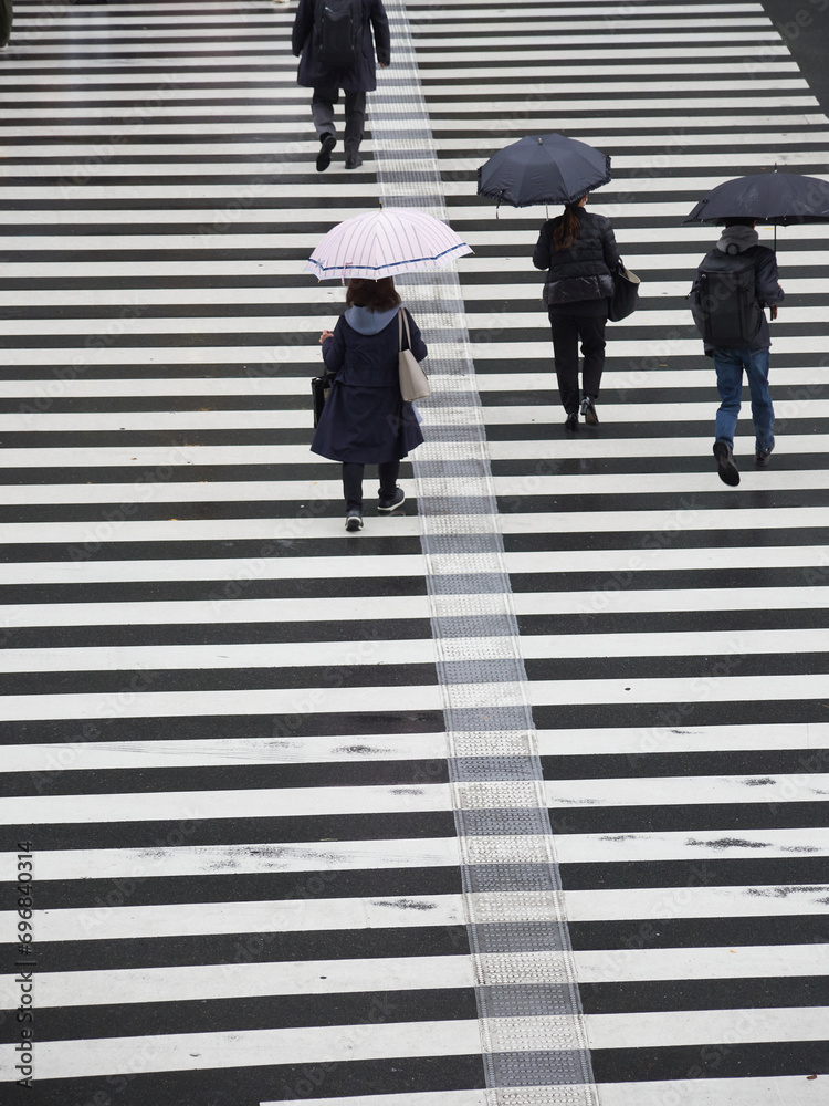 冬の雨の日に都市の交差点の横断歩道を渡る人々の姿、 冬の雨の日に都市の交差点の横断歩道を渡る人々の姿、