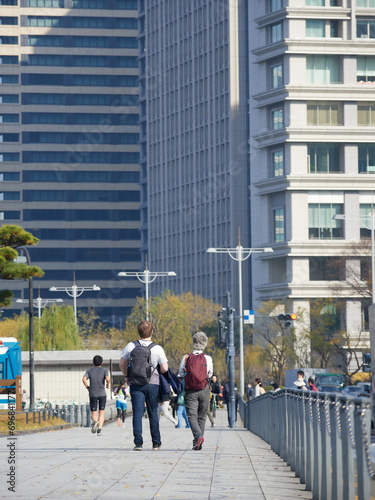 秋の皇居外苑の道で散歩している観光客と走るランナーたちの姿