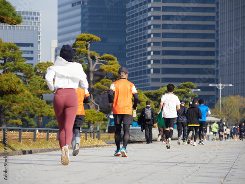 秋の皇居外苑の周辺で走るランナー達と東京都の都心の高層ビルの風景 photo