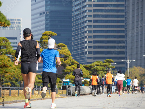 秋の皇居外苑の周辺で走るランナー達と東京都の都心の高層ビルの風景