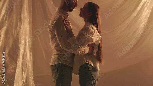 Slow motion shot of silhouette caucasian family hugging on blinking light background. Romantic couple cuddles in harmony indoors. Man and woman loves embrace. Sensual newlyweds dance photo