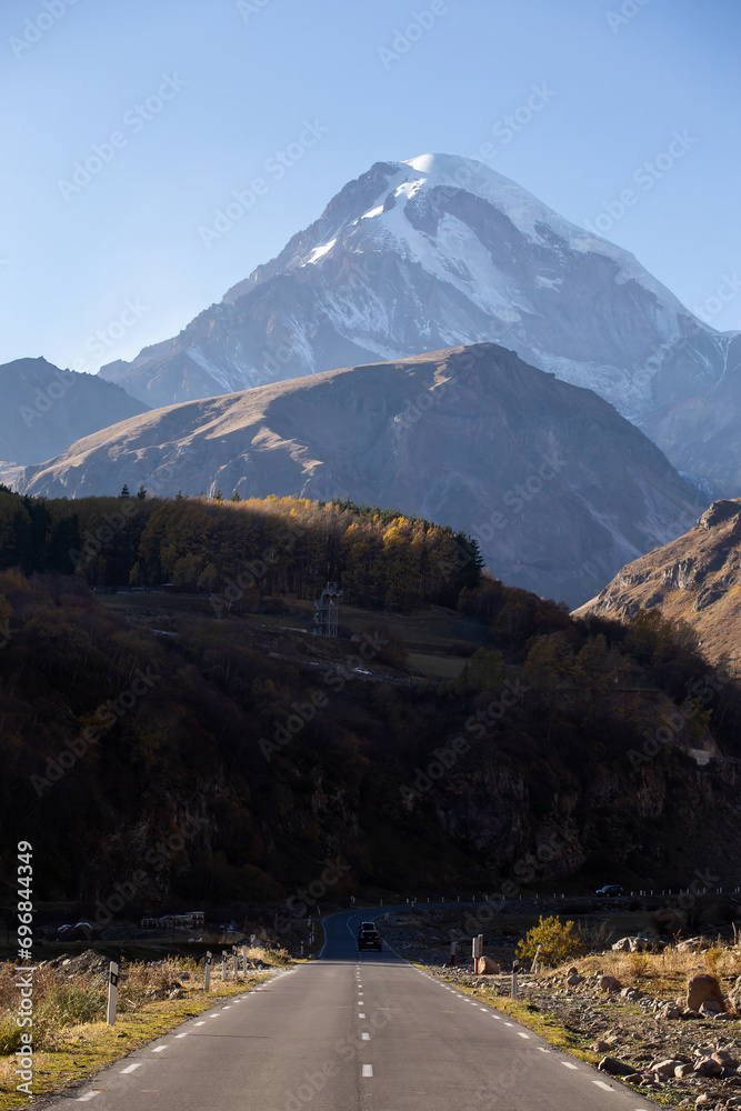road going towards the mountains, Mount Kazbek in autumn.