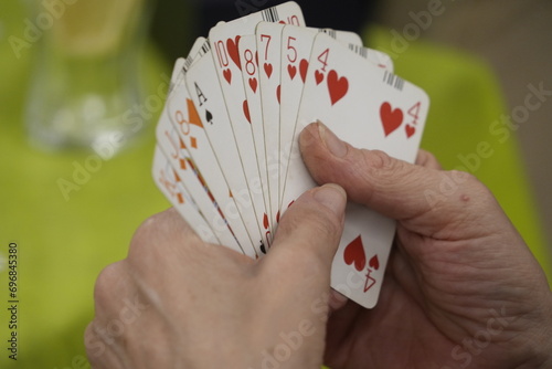Hands of unrecognizable people play a game of bridge cards on a green table