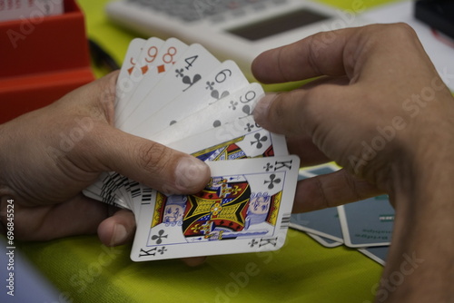 Hands of unrecognizable people play a game of bridge cards on a green table