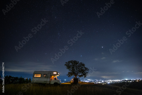 motorhome at night near a tree and starry sky
