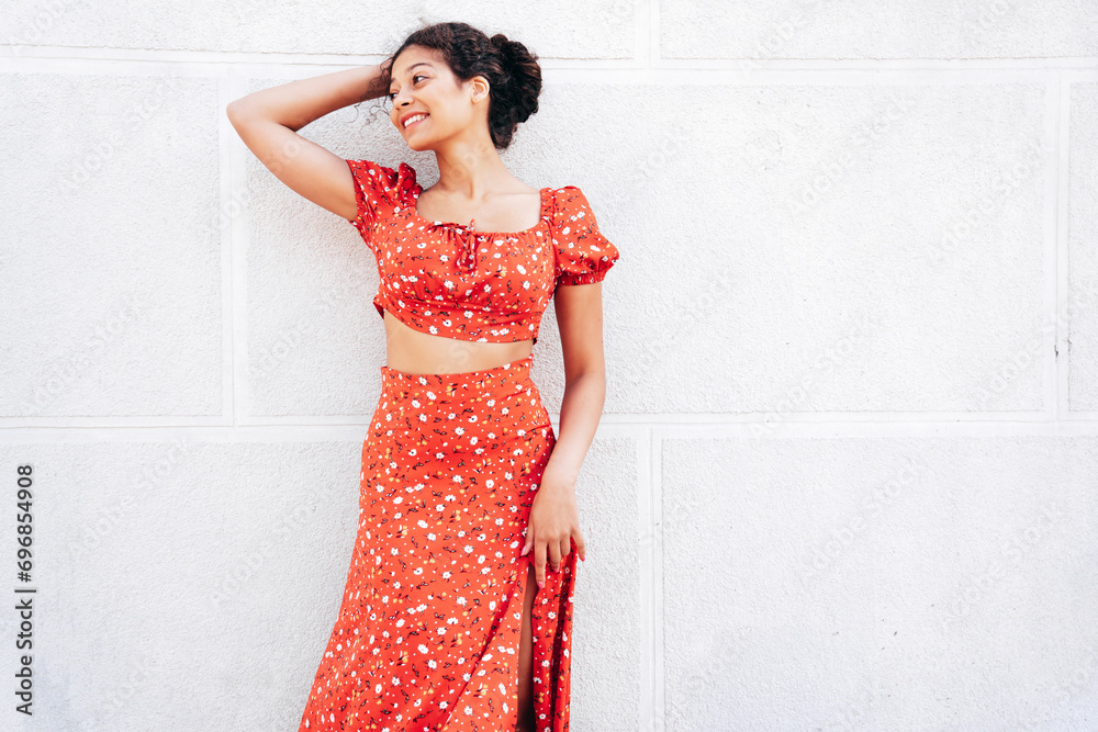 Young beautiful smiling hipster woman in trendy summer red dress. Carefree woman posing in the street near wall. Positive model outdoors in at sunny day. Cheerful and happy Young beautiful smiling hipster woman in trendy summer red dress. Carefree woman posing in the street near wall. Positive model outdoors in at sunny day. Cheerful and happy
