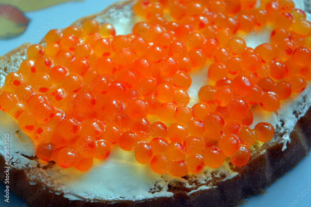 Food, homemade food, a sandwich with red caviar, namely a piece of white bread spread with butter and lined with red caviar. Food, homemade food, a sandwich with red caviar, namely a piece of white bread spread with butter and lined with red caviar.
