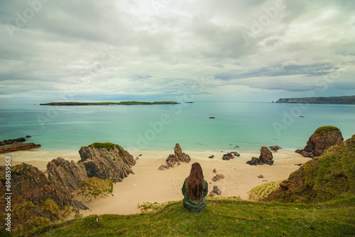 Exploring NC500's Top Beaches: A Gazing Girl on a Cliff, Embracing Scotland's Azure Sea Along the NC500 Route, Including Sango Sands, Balnakeil, and Achmelvich Beaches photo