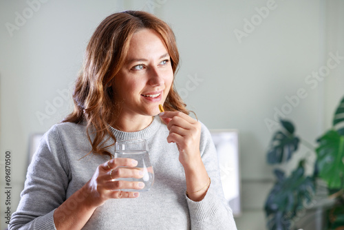 Young woman taking Omega 3 capsule